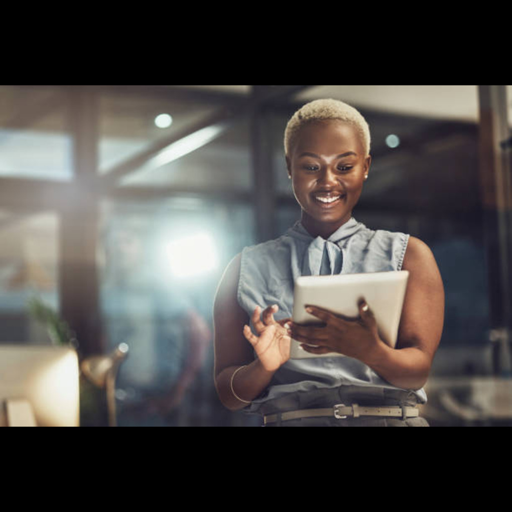 A smiling African woman using a tablet in a creative workspace, representing empowerment and success in the creative industries.